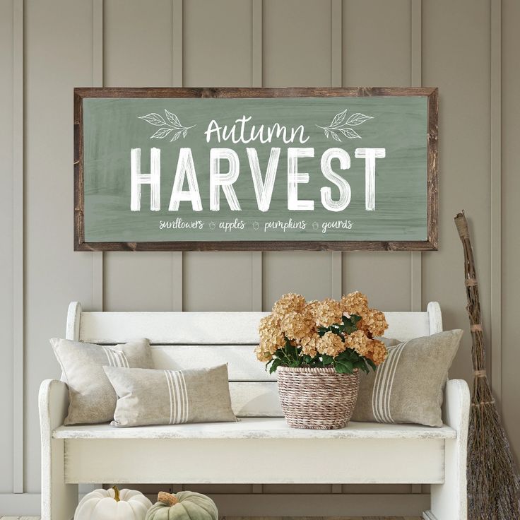 a wooden sign that says autumn harvest sits on a white bench with flowers and pumpkins