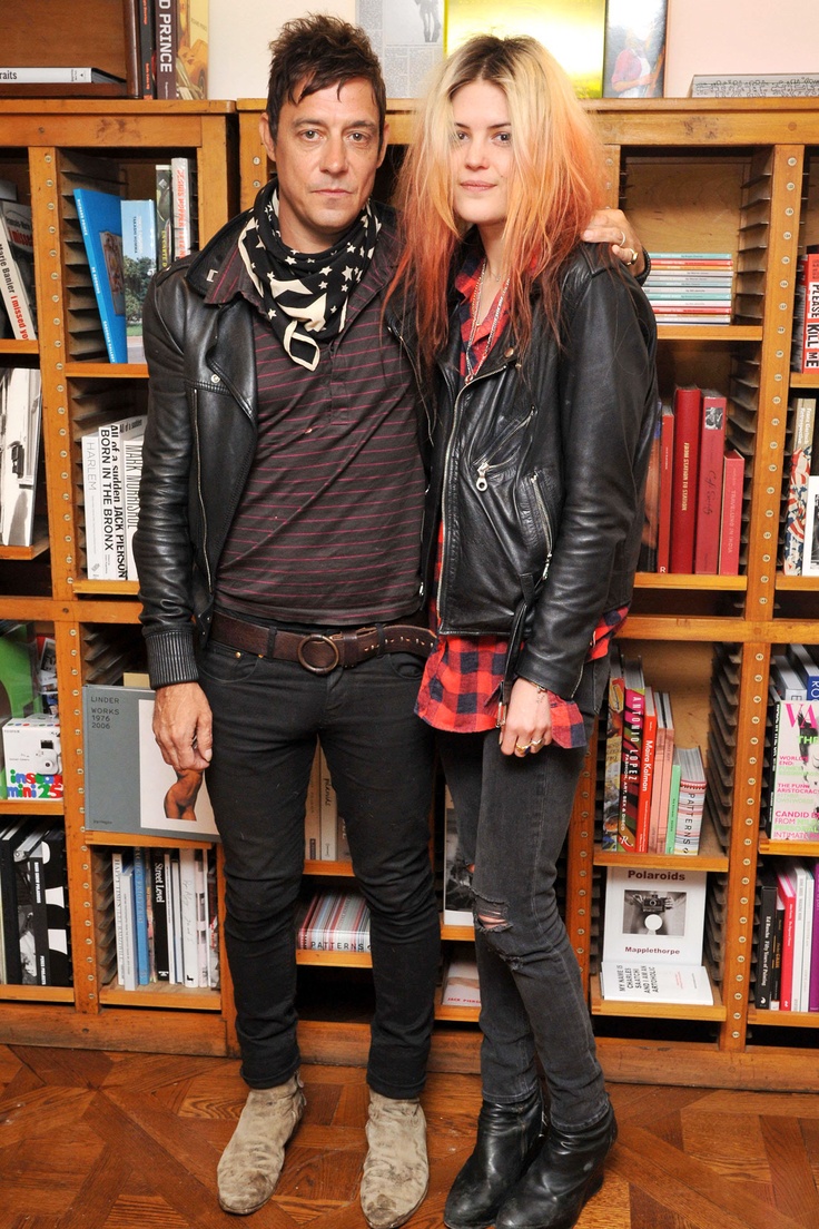 two people standing next to each other in front of bookshelves