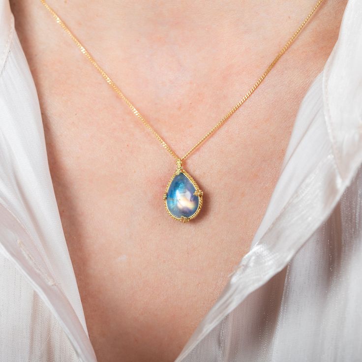 This Moonstone pendant shimmers with a swirling, blue iridescence. This one-of-a-kind gemstone is set in a meticulously hand-crafted gold setting with braided gold and granulated prongs. It’s strung on an 18k yellow gold chain. Technical Details Metal: 18k yellow goldMoonstone: 8.27 cts. Pendant Size (not including bail): 17mm x 13.5mmChain: can be worn at 16" and 18"Closure: lobster claspHandmade in New YorkStyle # N-3476-MO Gold Teardrop Cabochon Jewelry, Gold Cabochon Teardrop Pendant Jewelry, Gold Cabochon Teardrop Pendant, Gold Teardrop Pendant Necklace With Gemstone Accents, Gold Moonstone Necklace With Briolette Shape, Gold Moonstone Briolette Necklace, Gold Teardrop Necklace With Gemstone Accents, Elegant Opal Necklace With Wire Wrapped Detail, Gold Necklace With Moonstone Briolette