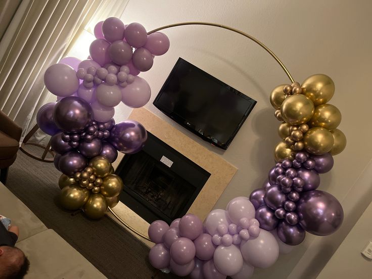 the balloon arch is decorated with gold, purple and silver balloons in an elegant manner