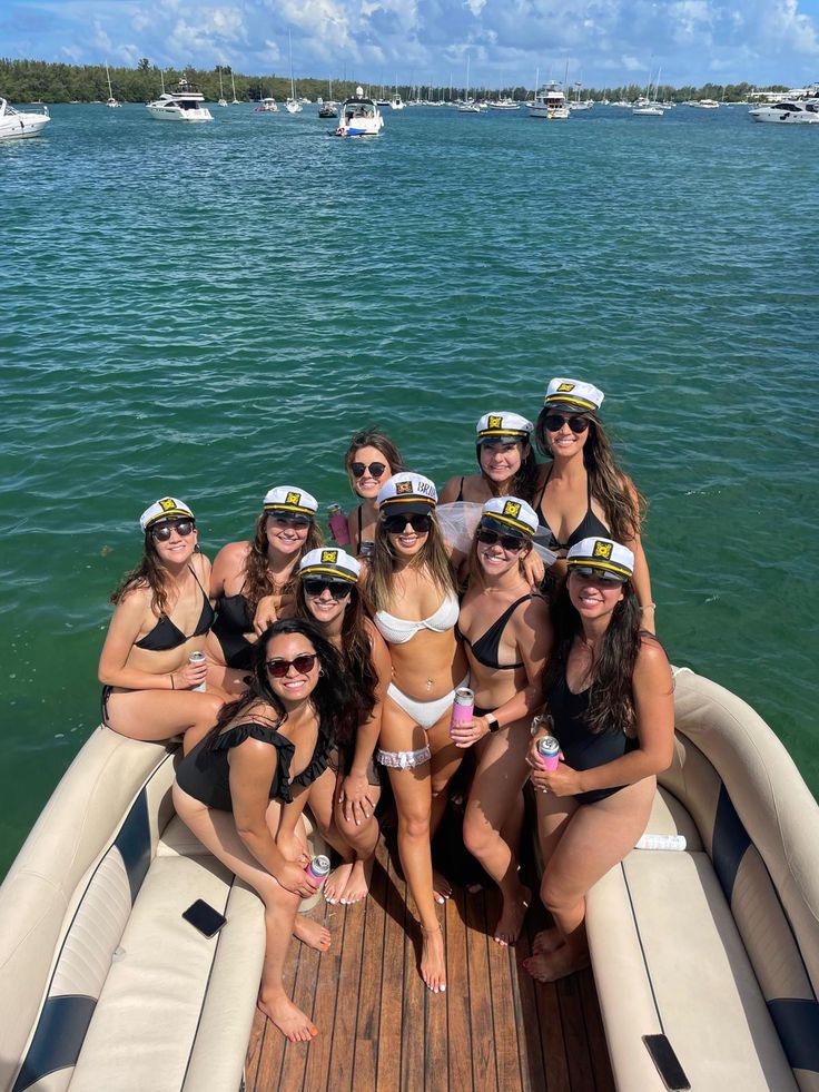 a group of women in bikinis on a boat posing for a photo with each other