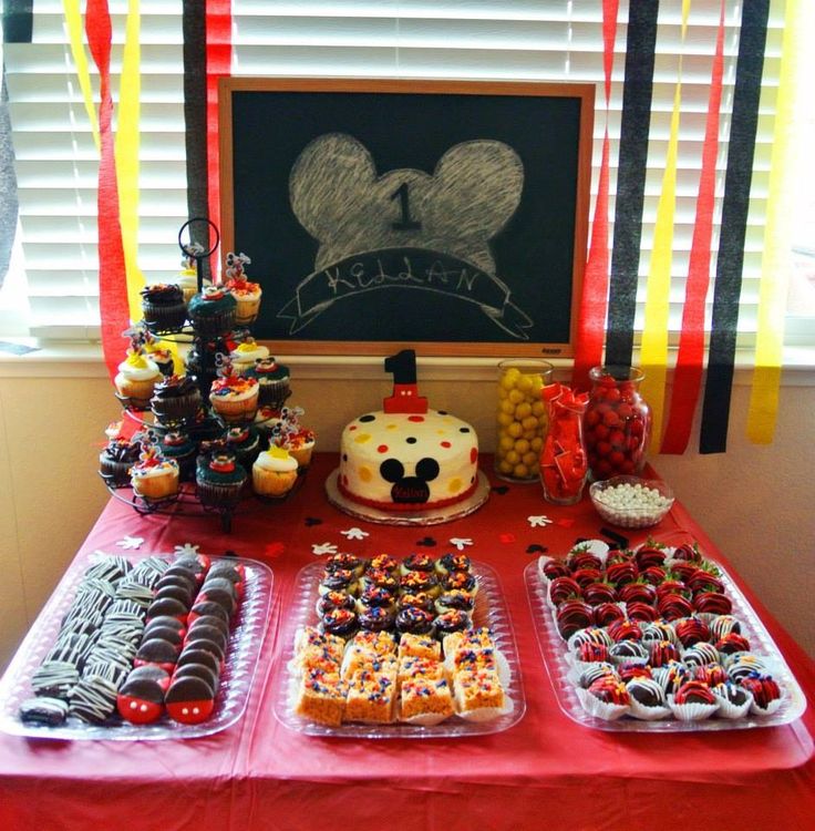 a table topped with lots of desserts next to a chalkboard and window sill