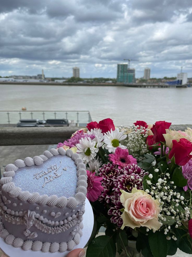 a heart shaped cake sitting on top of a table next to a vase filled with flowers