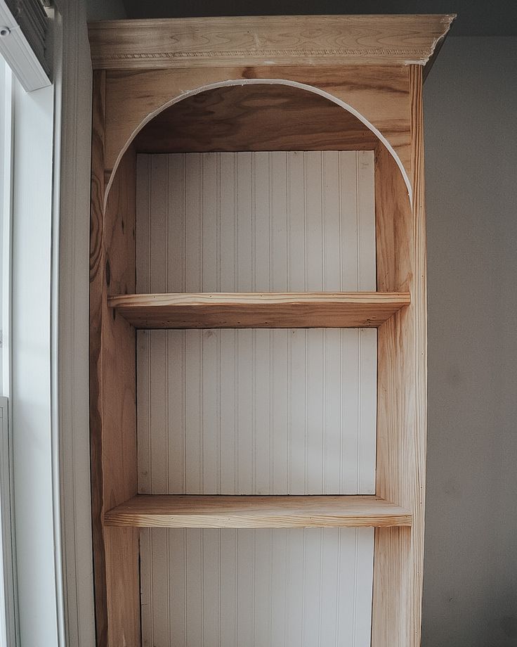 a wooden book shelf sitting next to a window