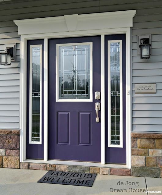 a purple front door with two sidelights and glass panels on the top half of it