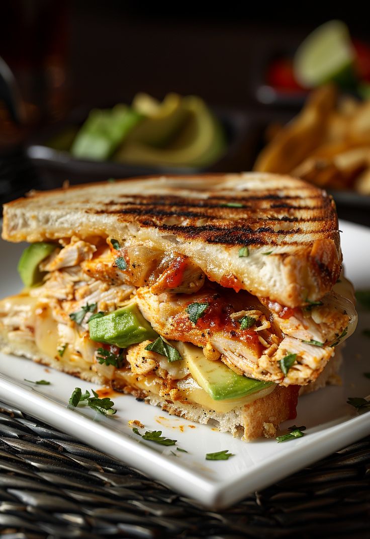 a grilled chicken sandwich on a plate with avocado