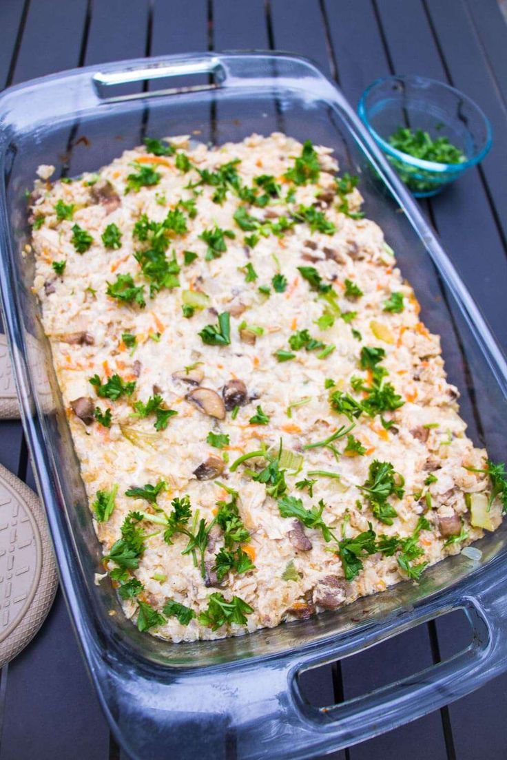 a casserole dish with mushrooms and parsley in it sitting on a table