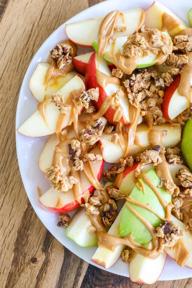 a white plate topped with apples and granola covered in caramel drizzle