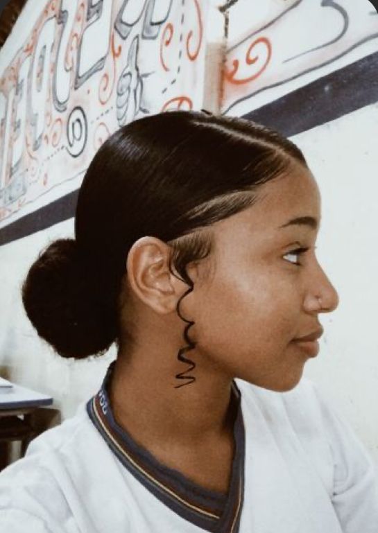 a woman with a tattoo on her neck sitting in front of a wall and looking off to the side