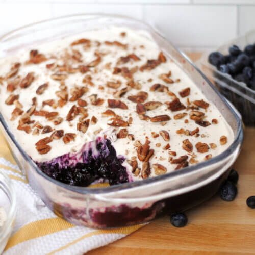 blueberry cobbler with yogurt and granola toppings on a wooden table