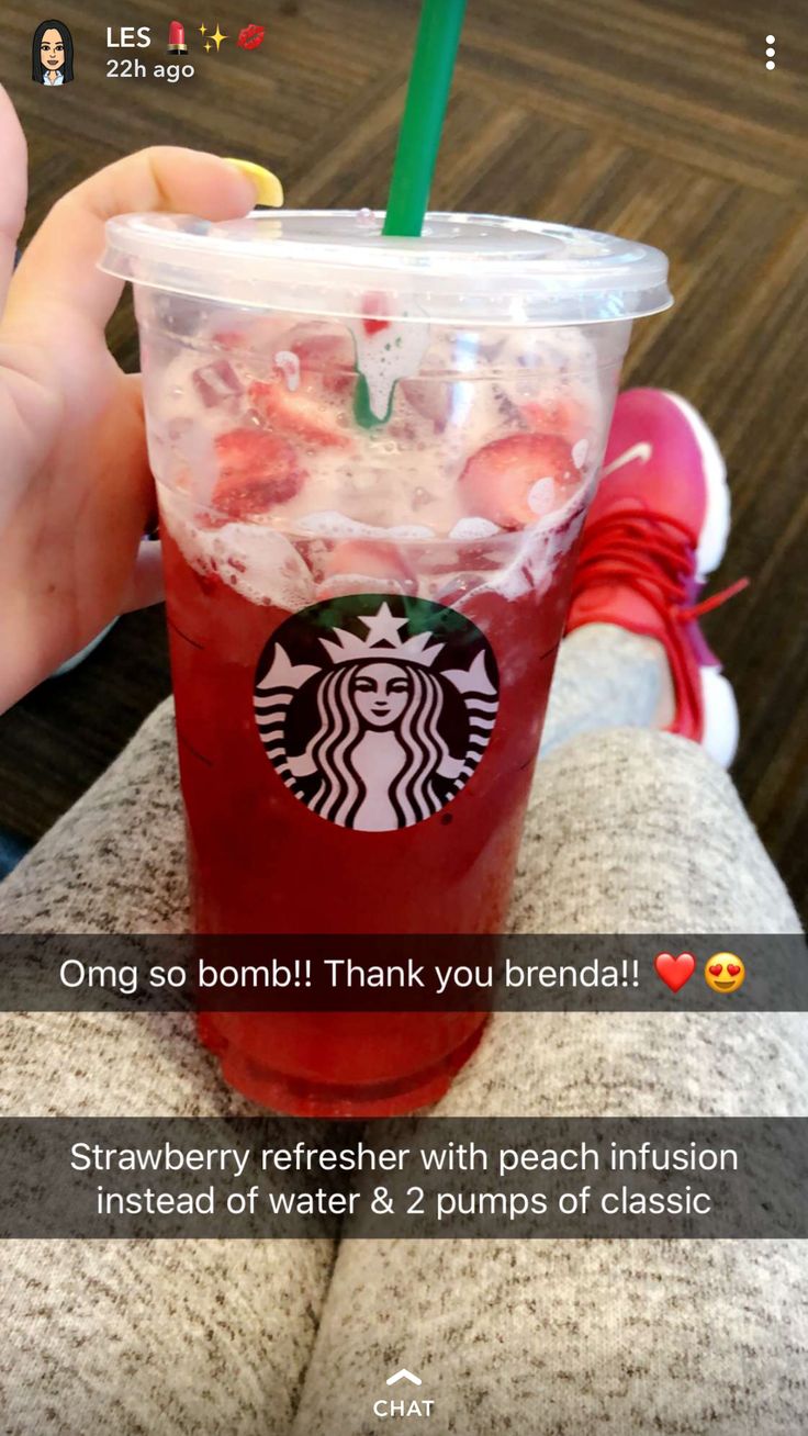 someone holding up a starbucks drink with strawberries in it