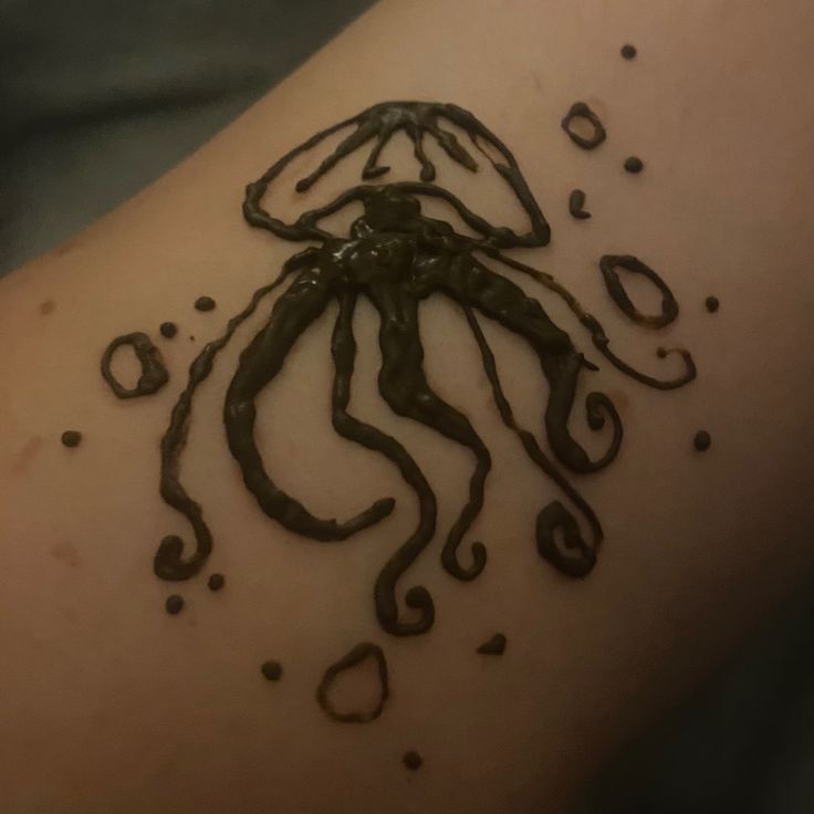 an octopus tattoo on the back of a woman's arm, with drops of water coming out of it