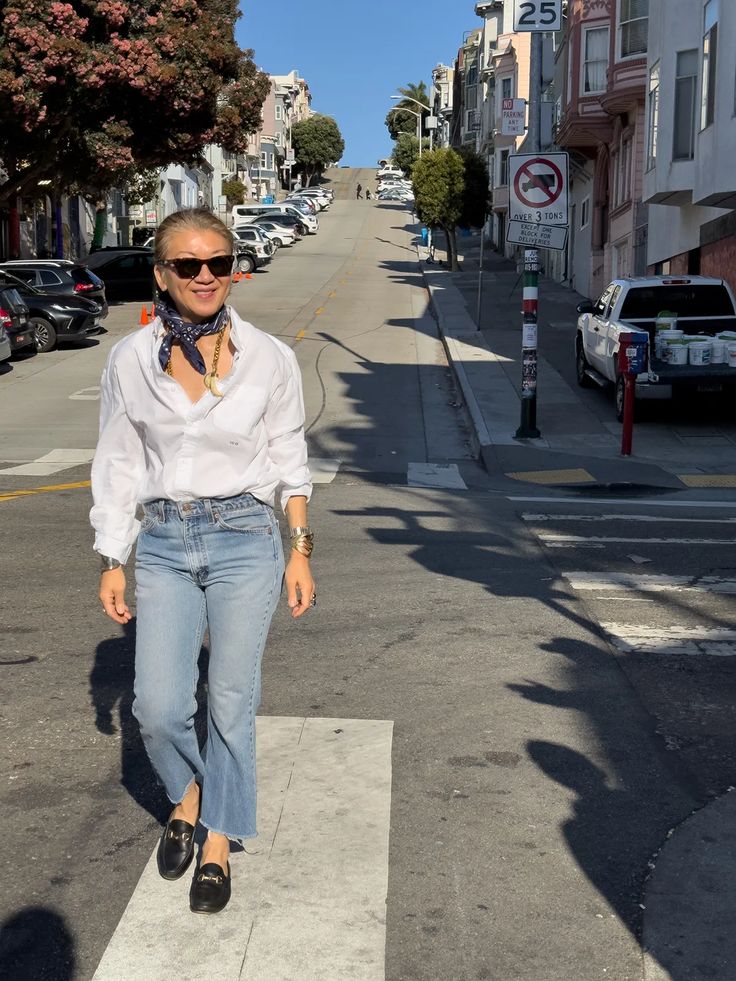 a woman walking across a cross walk on the street