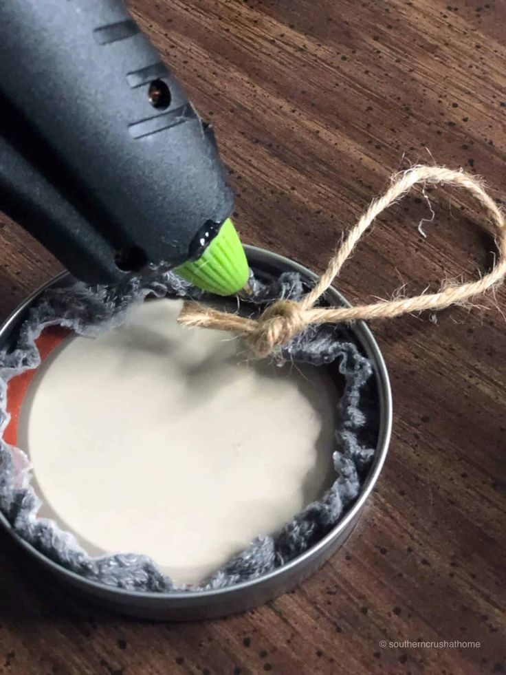 a hair dryer sitting on top of a wooden table next to a tin filled with white liquid