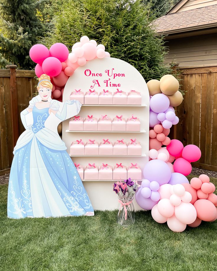 a princess themed birthday party with balloons, cake and candy bar for one upon a time