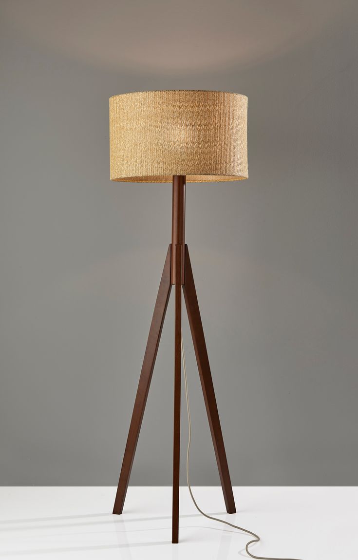 a floor lamp with a wooden tripod base and a light shade on the top