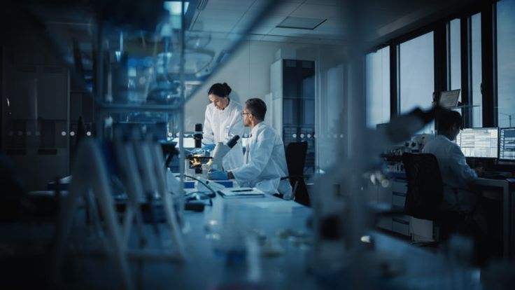 two people in white lab coats working on some type of equipment with microscopes and test tubes