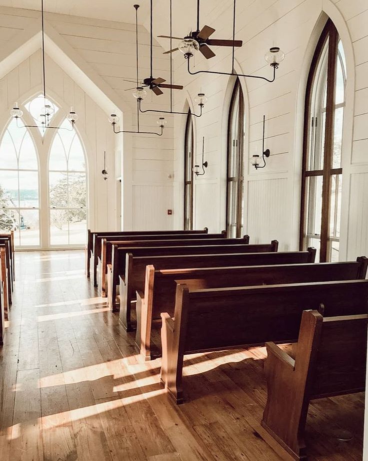 an empty church with wooden pews and stained glass windows