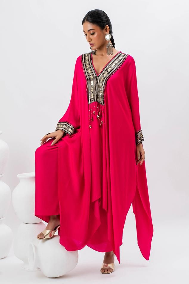 Pink kaftan kurta with hand embroidered ajrakh border lace on yoke in front. Paired with stitched wrap skirt.
Components: 2
Pattern: Embroidered
Type Of Work: Ajrakh, Sequin, Zari, Thread
Neckline: V Neck
Sleeve Type: Batwing
Fabric: Satin
Color: Pink
Other Details: 
Tassel details
Asymmetric hem
Occasion: Mehendi and Haldi - Aza Fashions Ajrakh Border, Pink Kaftan, Kaftan Kurta, Border Lace, Types Of Work, Satin Color, Pink Satin, Set For Women, Bat Wings