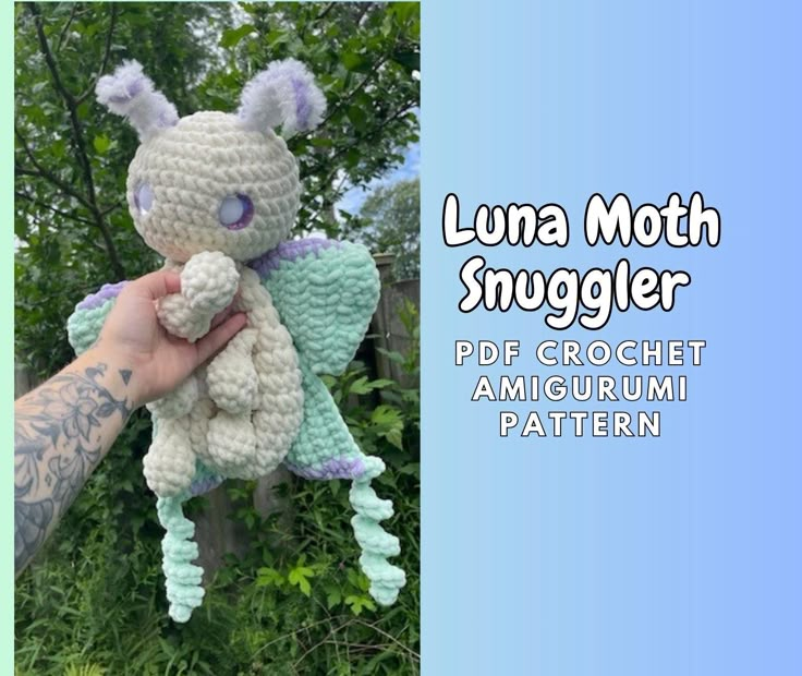 a hand holding a stuffed animal in front of some trees and bushes with the words luna moth snuggler on it