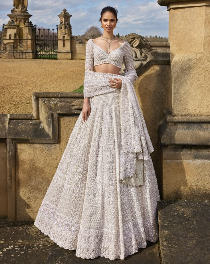 This nude lehenga set features intricate embroidery in thread, pearl, and sequin in a geometric pattern. The fully embroidered blouse has exaggerated tassels at the elbow. The dupatta has four sided heavy embroidery with a geometric jaal in the center.From Seema Gujral's A Royal Affair collection. DELIVERY TIMEPlease allow 8-12 weeks for your outfit to arrive. FABRIC DETAILSNet Professional cleaning only. Wedding Lengha Bridal Lehenga, Nude Lehenga, Pearl Lehenga, Pearl Tassels, Seema Gujral, Chikankari Lehenga, A Royal Affair, White Lehenga, Lehenga Dupatta