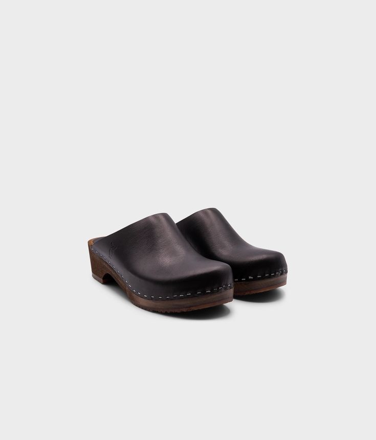 Elevate your everyday style with our minimalist clog mule, featuring clean lines and a timeless aesthetic that effortlessly transitions from day to night. Clog measurements:Heel height: 1 3/4” (4.5 cm)Toe height: 1 5/8″ (4.1 cm) Fit:RegularLeather:Vegetable tanned leather Clogs consist of:Base: European Lime Wood Sole: Rubber sole Fastening: Staples Clog Shoes For Women, Fall Clogs, Black Clogs, Cork Sandals, Wooden Clogs, Timeless Aesthetic, Clog Heels, Sustainable Future, Clog Sandals