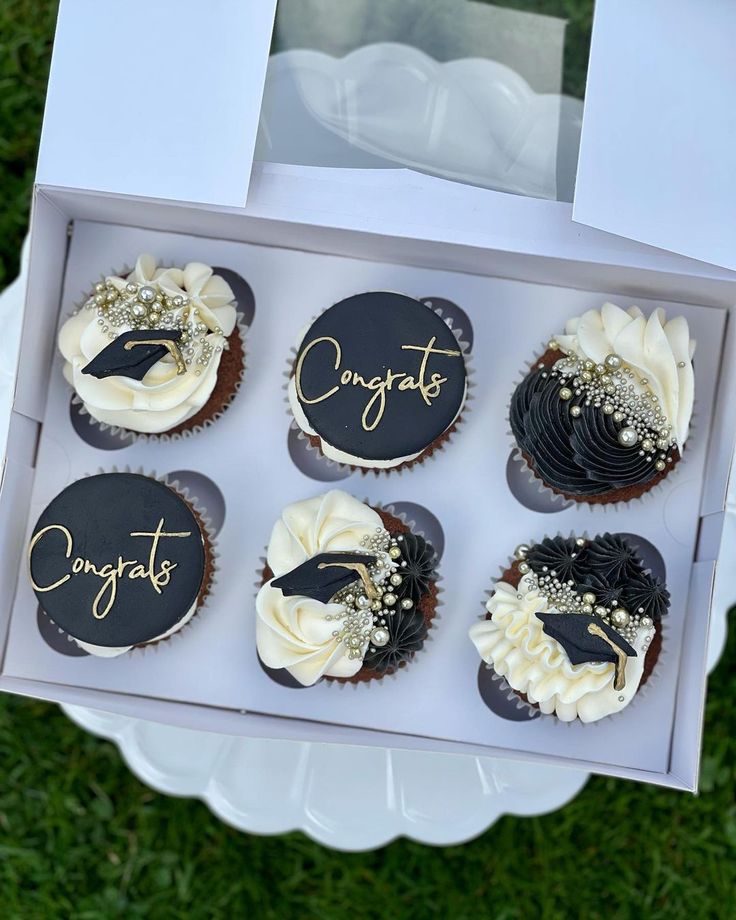 cupcakes with black and white frosting are in a box on the grass