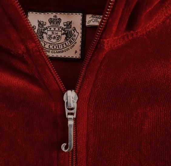 a close up of a brown sweater with a badge on the collar and zippers