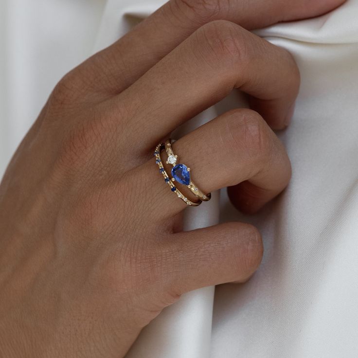 a woman's hand wearing a gold ring with blue stones