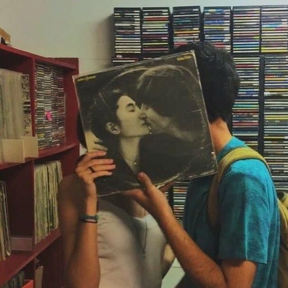 a man holding up a record in front of a woman's face with an album on it