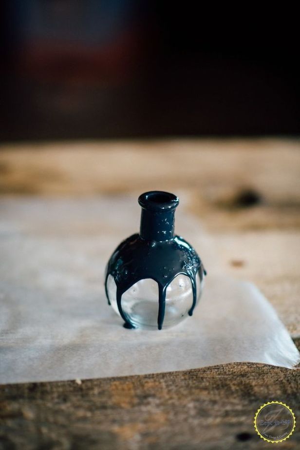 a small black vase sitting on top of a piece of paper with water in it