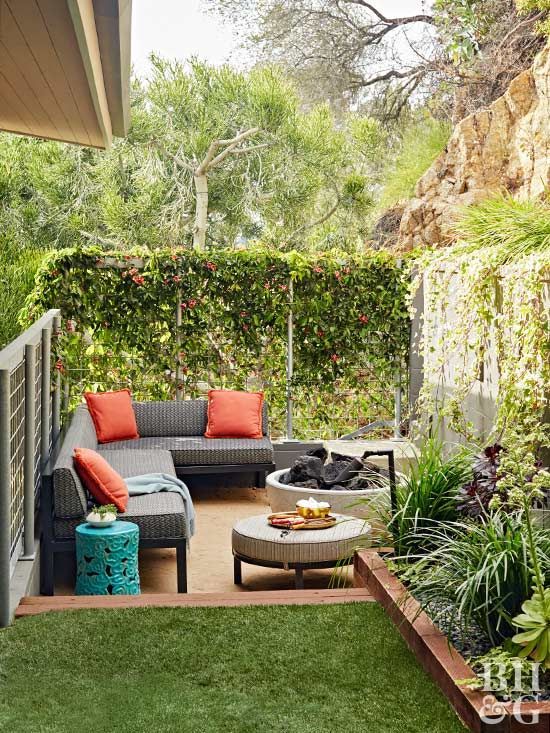 an outdoor living area with couches, tables and plants on the side of it