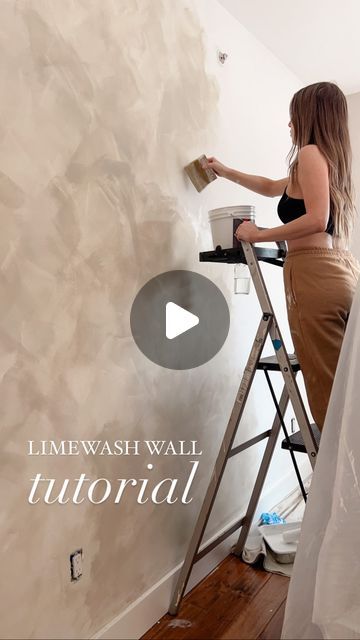 a woman is painting a wall with white paint