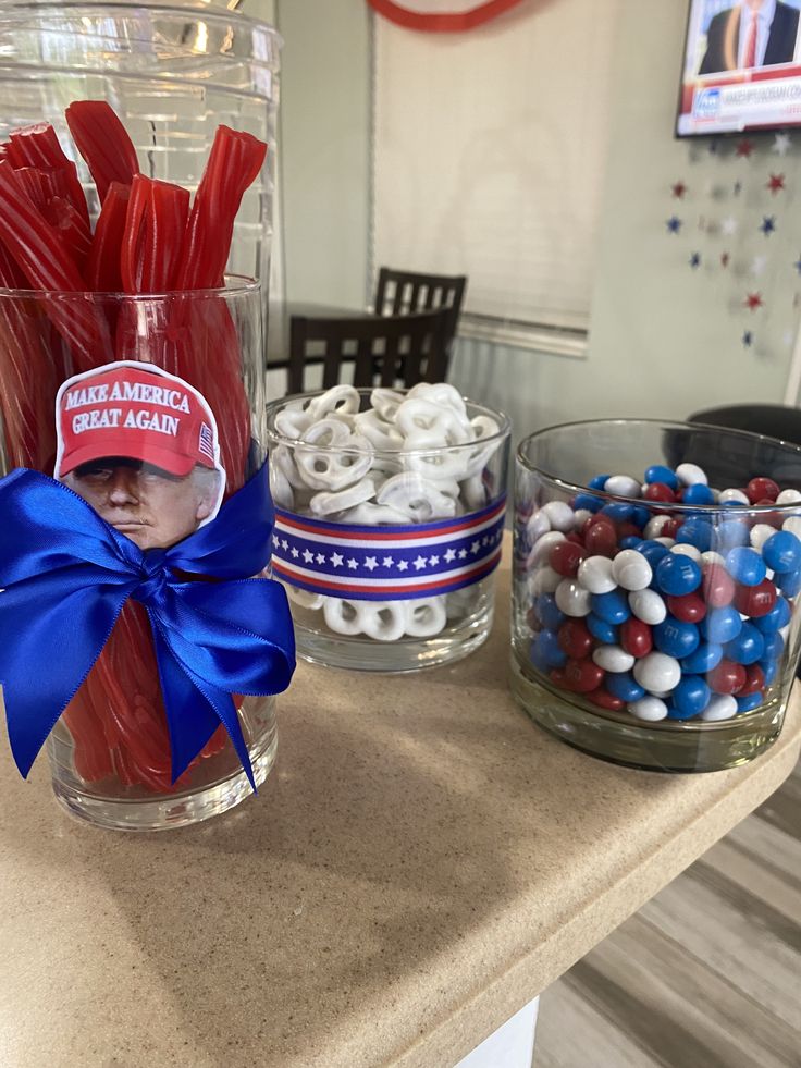 there are many patriotic items in the glass vases on the counter and one is red white and blue