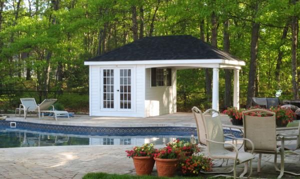 a backyard with a pool and gazebo surrounded by trees