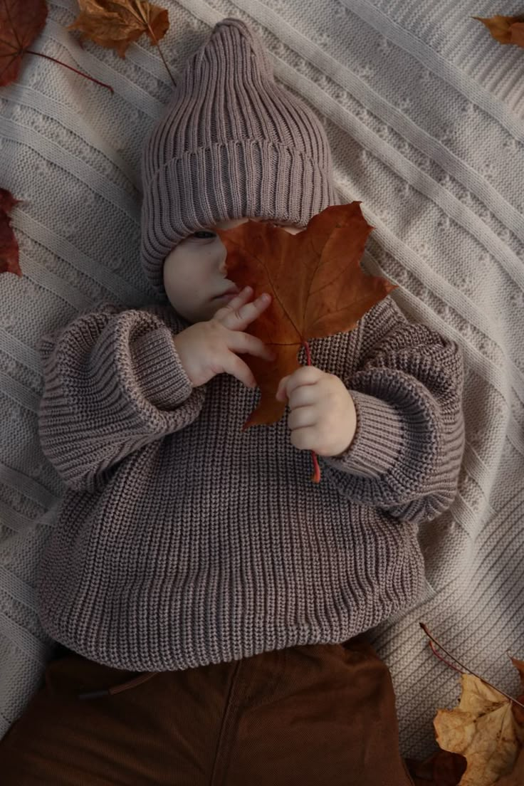 a baby is laying down with a leaf