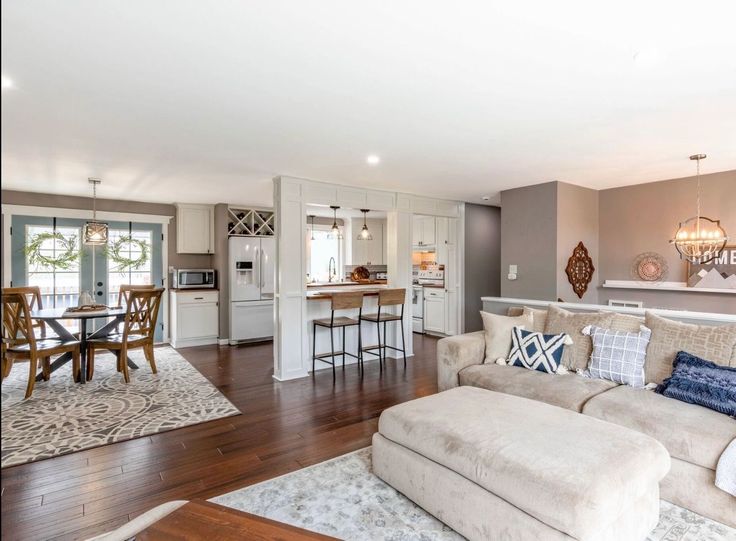 a living room filled with furniture next to a kitchen and dining room table on top of a hard wood floor