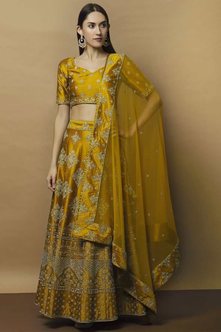 Green tinted yellow lehenga with all-over floral motif work. Comes with blouse and lace trim border embellished dupatta.
Components: 3
Fabric: Dupion Raw Silk
Neckline: Leaf
Sleeve Length: Half
Color: Green, Yellow
Embroidered
Tassel tie-up detail
Kamar latkans
Deep u-back blouse
Closure:
Lehenga: Side zip
Blouse: Side zip - Aza Fashions Semi-stitched Lehenga With Gold Embroidery For Reception, Wedding Lehenga With Gold Embroidery For Eid, Festive Raw Silk Lehenga With Gold Embroidery, Traditional Raw Silk Lehenga With Gold Embroidery, Traditional Lehenga With Gold Embroidery In Raw Silk, Festival Raw Silk Lehenga With Gold Embroidery, Tissue Silk Lehenga With Gold Embroidery For Festivals, Traditional Lehenga With Gold Embroidery, Eid Reception Lehenga With Gold Embroidery