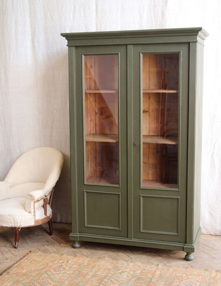 a green cabinet sitting next to a white chair on top of a carpeted floor