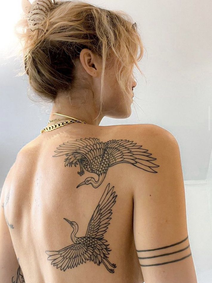 the back of a woman's body with tattoos on her upper and lower half