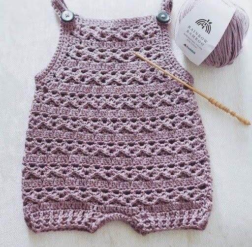 a crocheted baby sweater next to a ball of yarn