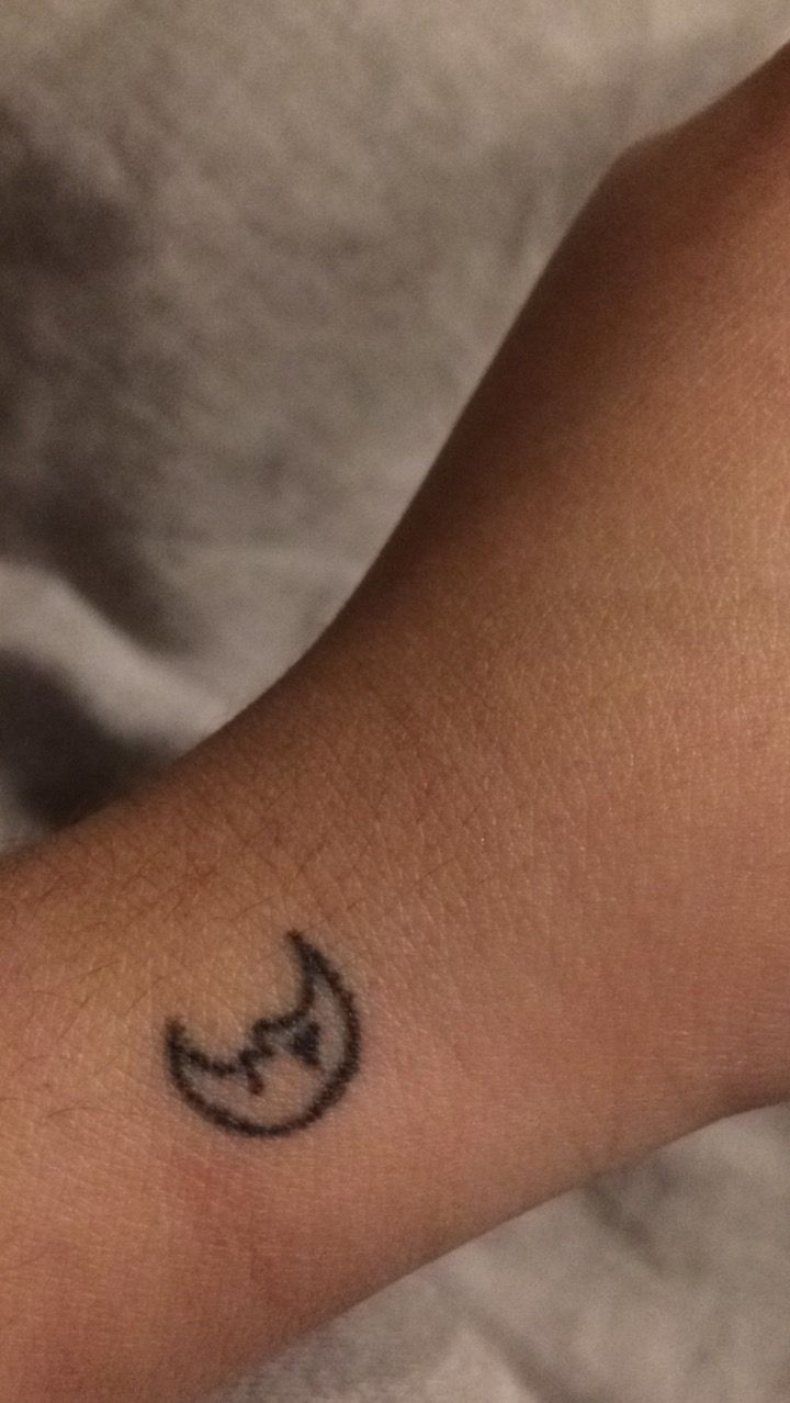 a small tattoo on the arm of a person with a crescent moon and star symbol