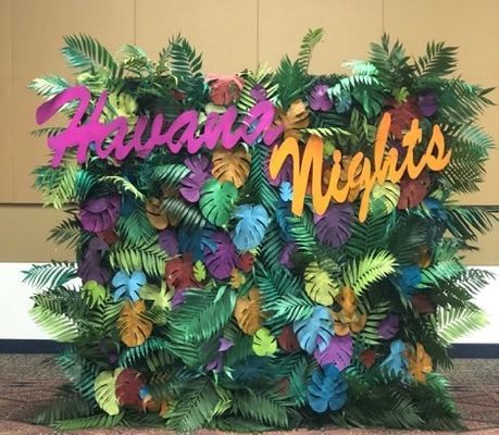 there is a sign that says hawaiian nights on the side of a wall with tropical leaves