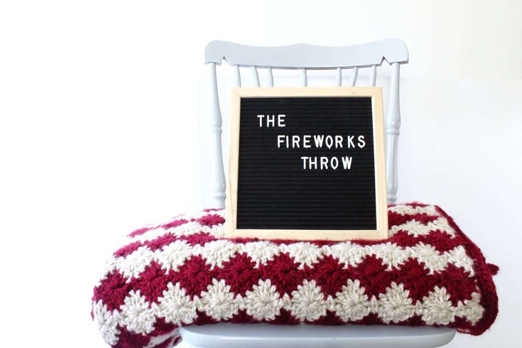 a sign that reads the fireworks throw sitting on top of a chair with a red and white blanket