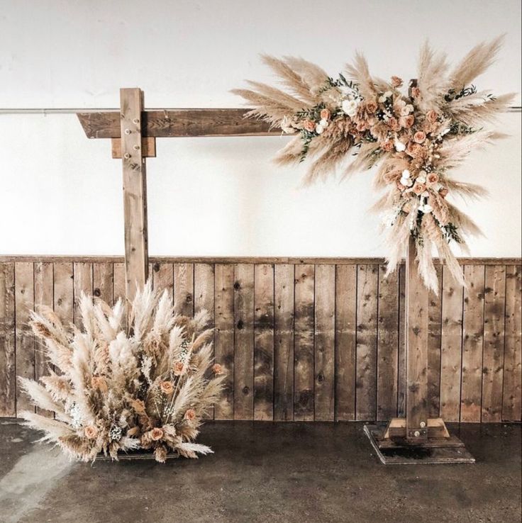 an arrangement of dried flowers on display in front of a wooden wall with planks