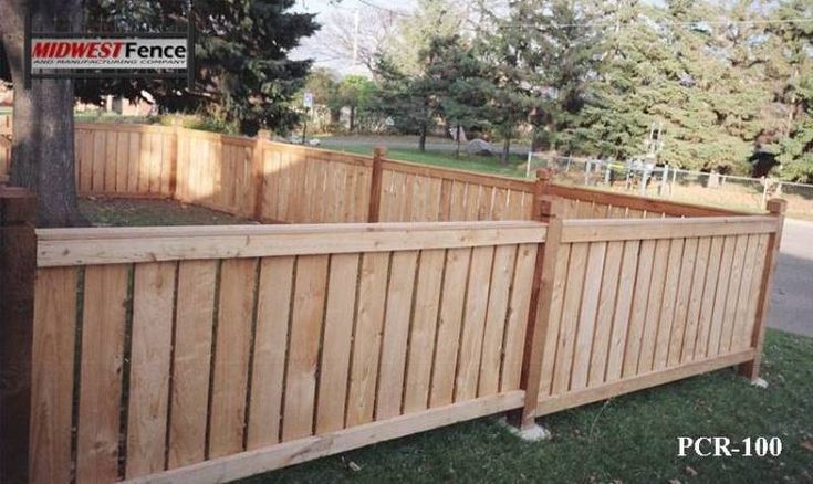 a wooden fence is in the grass next to a tree