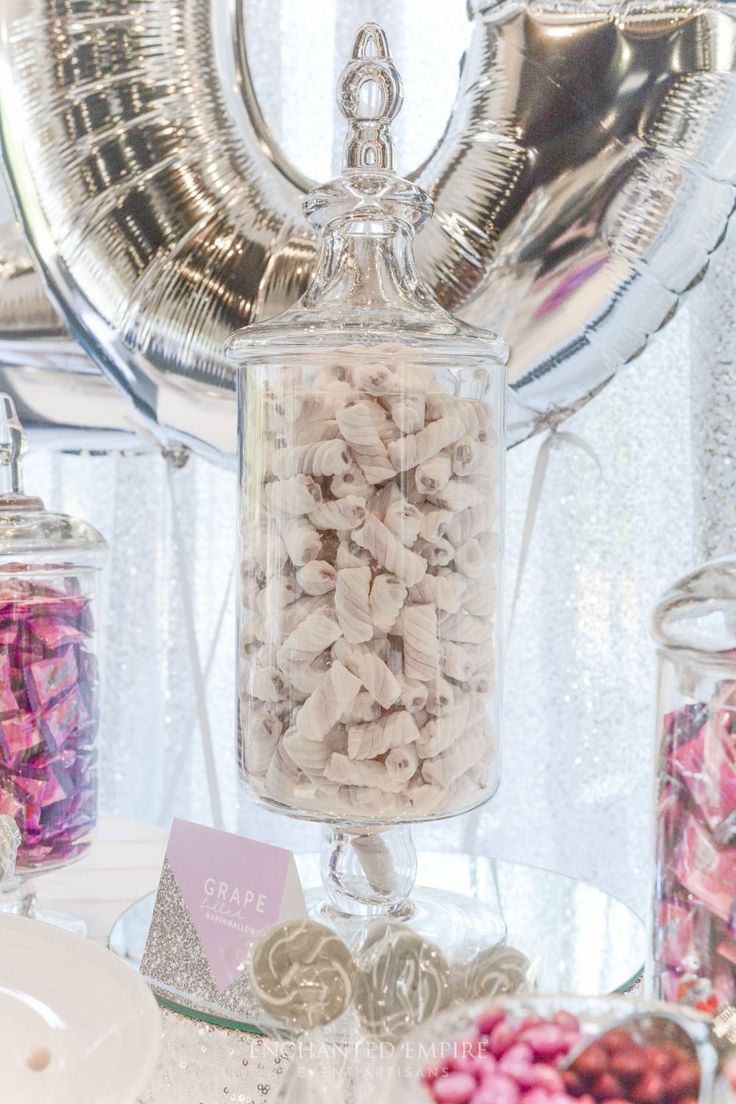 there are many candies in the glass jar on the table next to the balloon