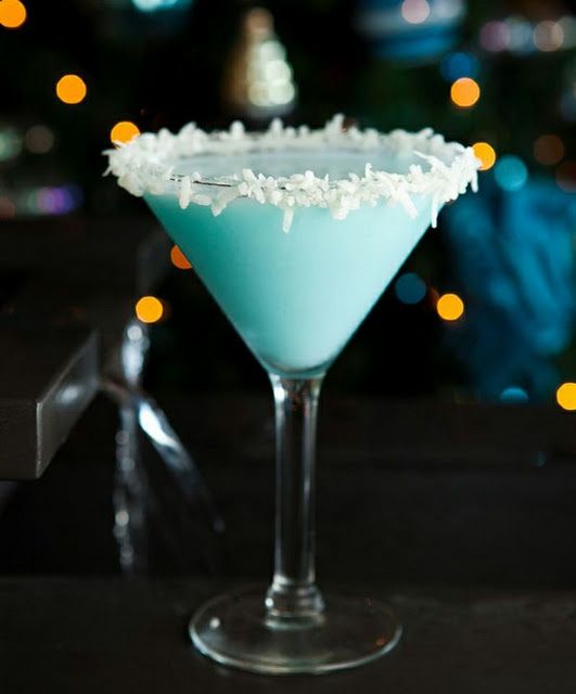 a blue drink with white snow flakes on the rim and garnished in coconut