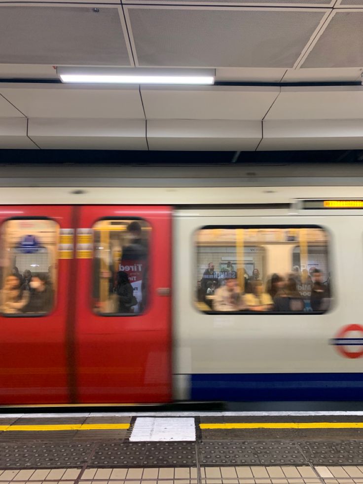 a subway train with many people on it's side, passing through the station