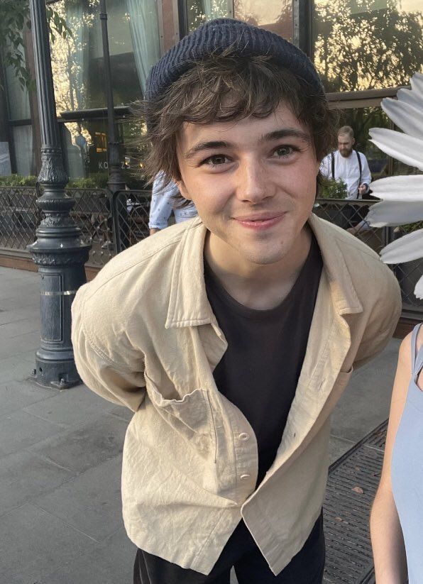 a young man standing next to a white flower